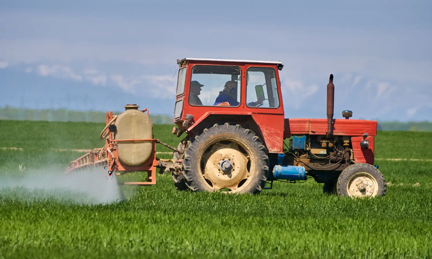 Produtores rurais aplicando defensivos químicos com trator