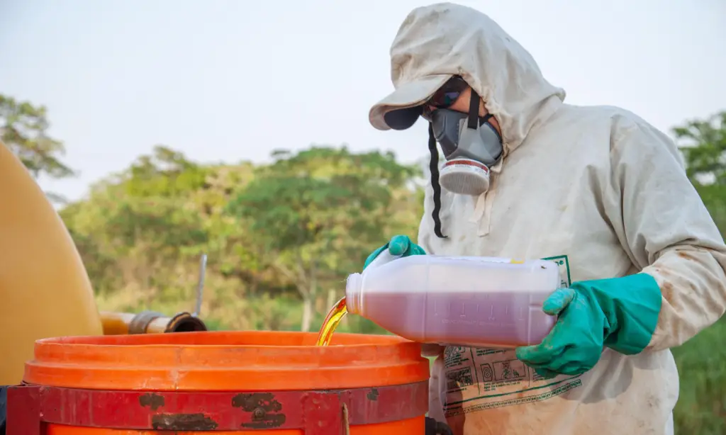 Trabalhador rural preparando a calda para aplicação de defensivos agrícolas