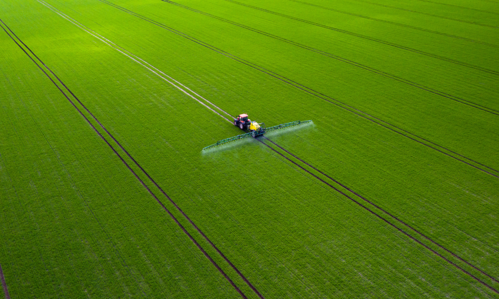 Imagem aérea de aplicação de defensivos agrícolas na lavoura por meio de trator