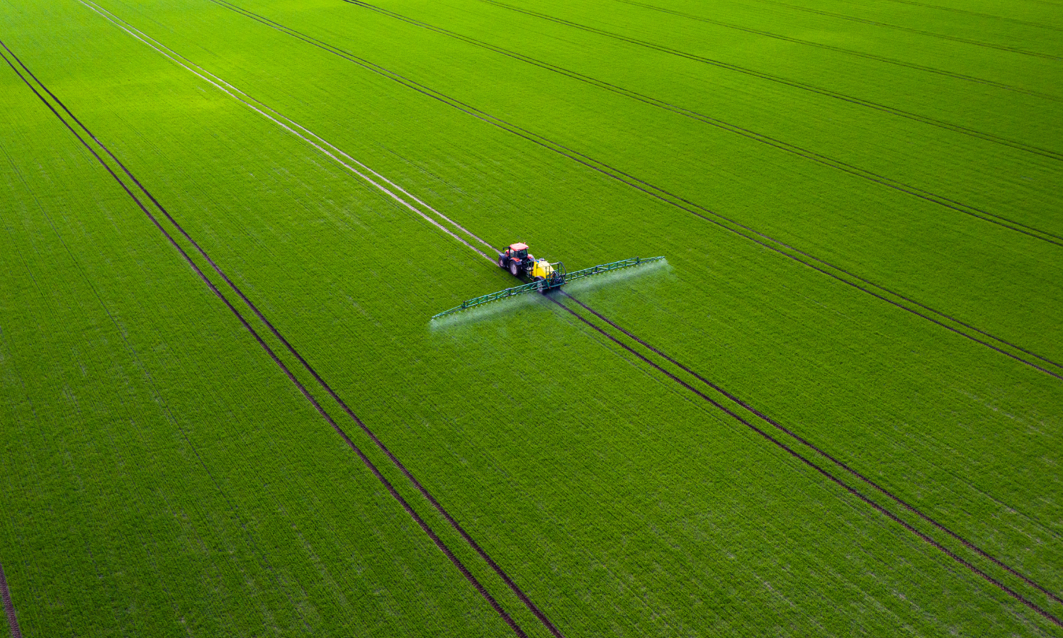 Imagem aérea de aplicação de defensivos agrícolas na lavoura por meio de trator